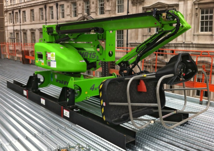 HR15 4x4 DeckRider® on a structural floor Niftylift HR15 4x4 in DeckRider configuration, its steel skid assemblies positioned on the metal decking of a structural floor