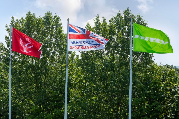 The Armed Forces Day flag flies alongside Niftylift flags outside the company's Milton Keynes headquarters, with an HR12 4x4 in the foreground.