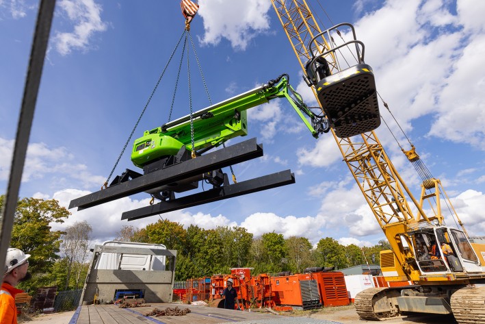 Lifting a DeckRider® by crane Close-up of a Niftylift DeckRider being lifted by crane, with chains attached to the dedicated lifting points on the steel skids