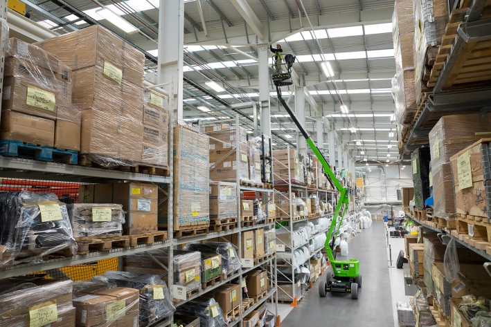 HR12N MK3 working over racking HR12N MK3 operating inside a factory environment reaching over industrial racking.
