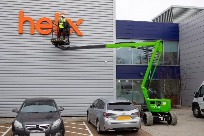HR12 4x4 reaching up and over parked cars to access a factory sign
